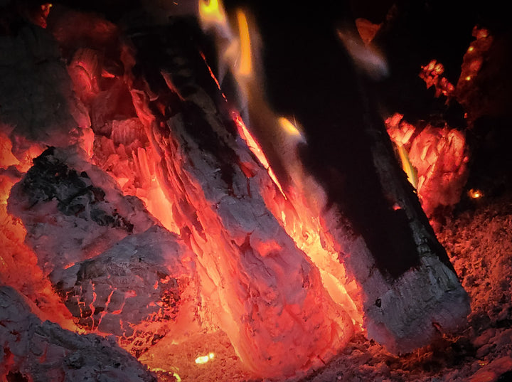 Several wood splits that have been burned down into a very hot, glowing red coalbed within the firebox of an offset smoker